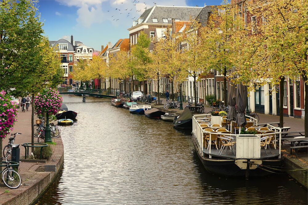 Een Leidse gracht met woonboten en terrassen, met herfstkleuren langs de kade
